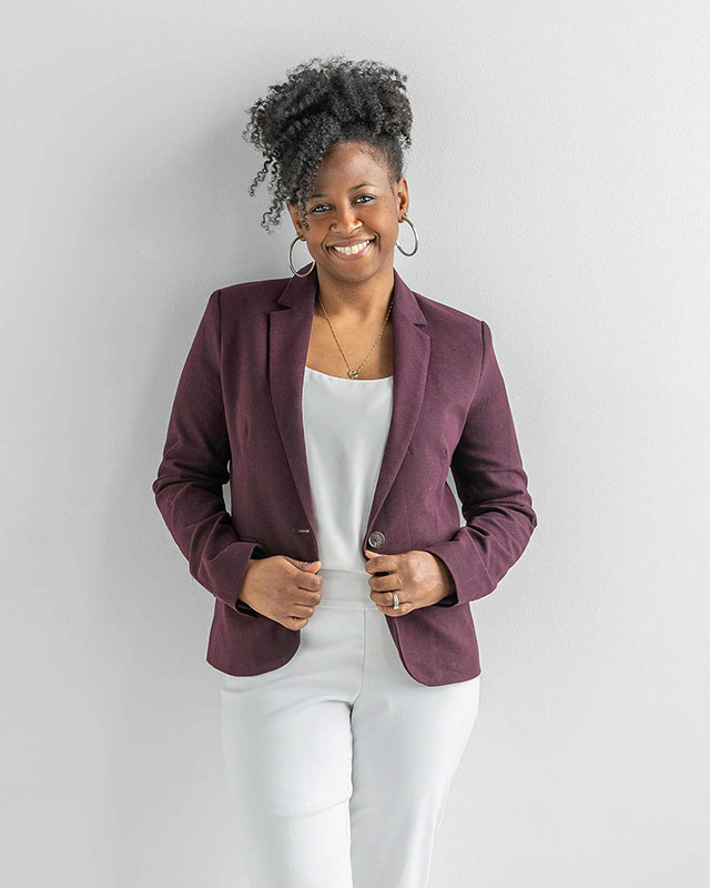 female executive posing for a corporate headshot wearing purple jacket on white