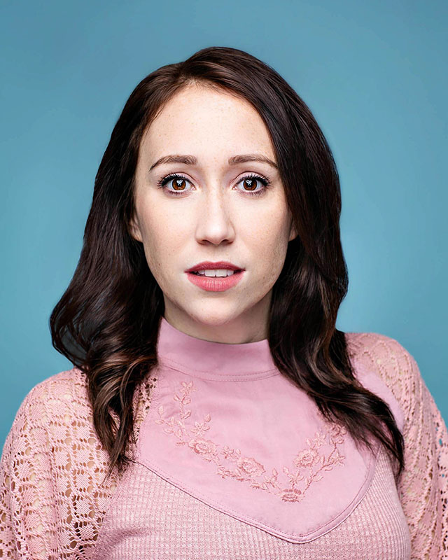 actor posing for a headshot blue background and pink top