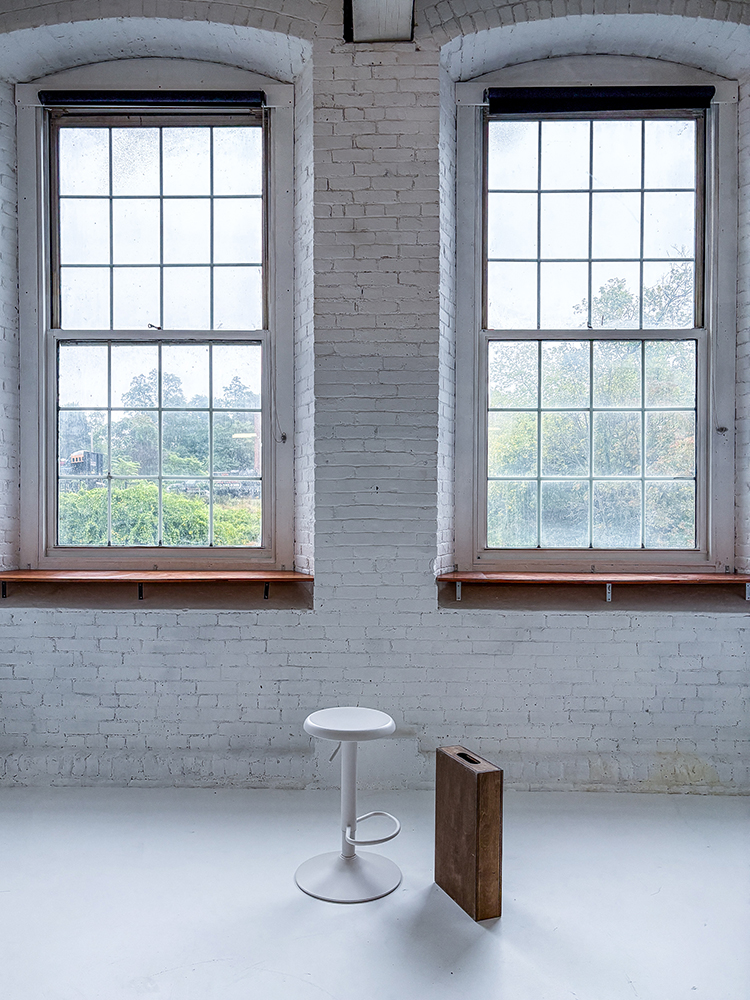 interior photograph of a portrait studio with white floor large windows and white brick